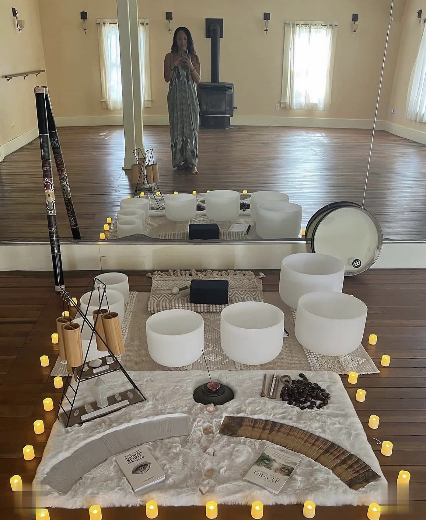 A sound bath setup in the studio: crystal singing bowls, chimes, and candles on a fur rug