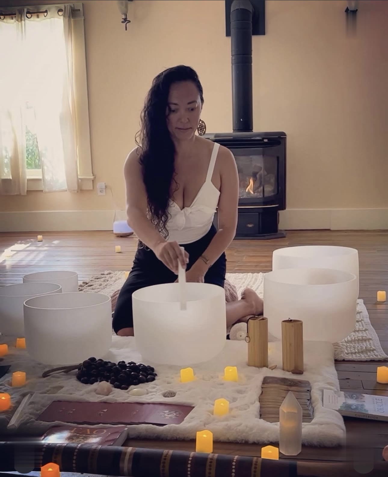 A teacher playing crystal singing bowls by the fire