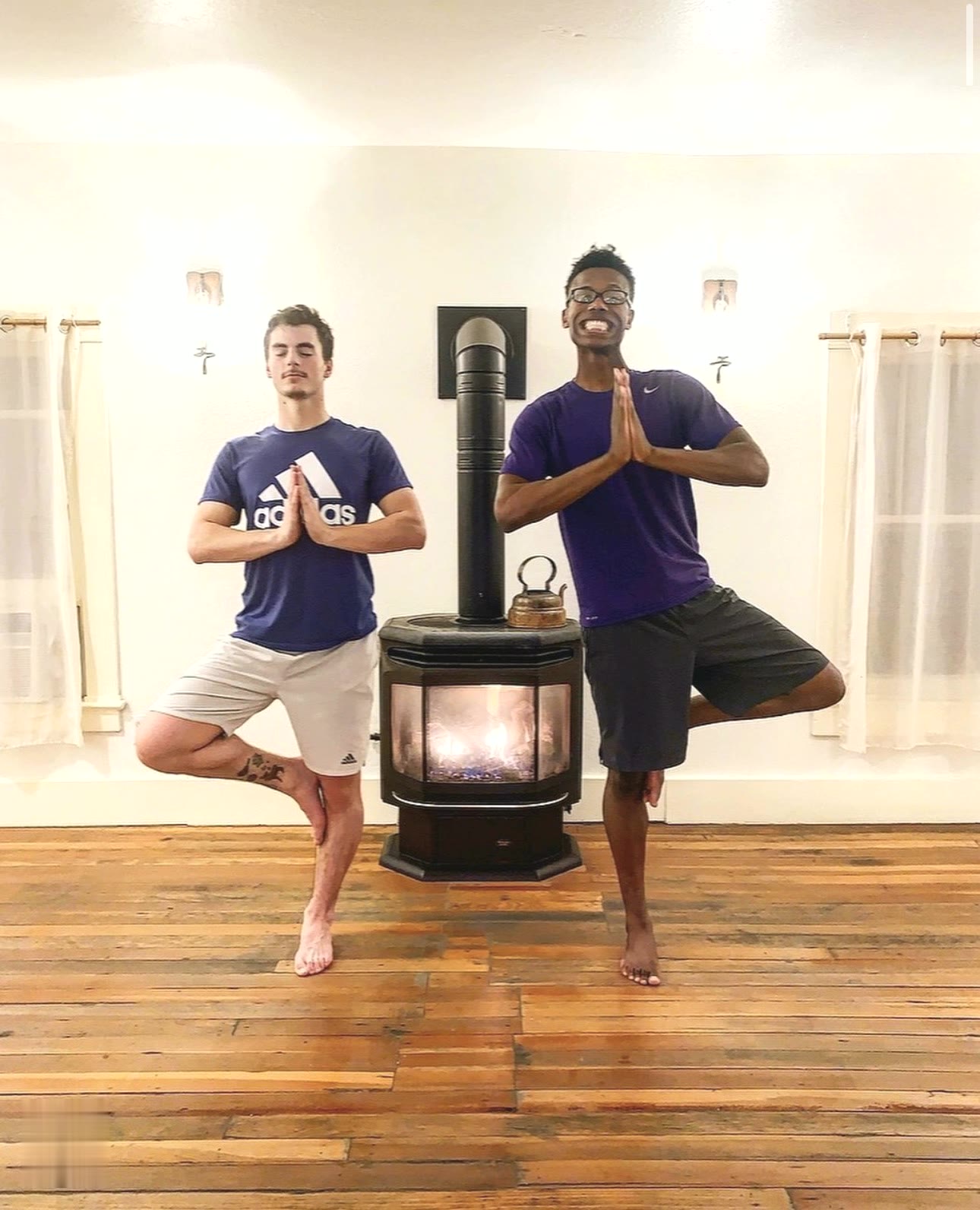 Two friends in tree pose by the wood stove